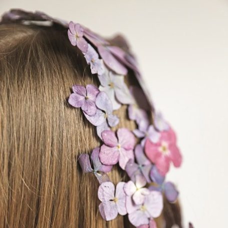Langes Haar mit einer dekorativen Kopfbedeckung aus violetten Hortensien Blüten.