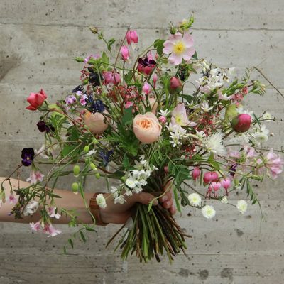 Bunte Blumenstrauß aus verschiedenen Blumen in einer Hand gehalten. Trockenblumen und Frischblumen, rosa, apricot, violett.
